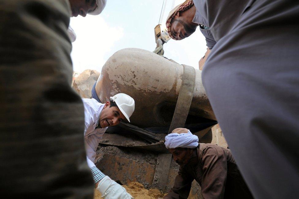 Egyptian workers stand as a statue is raised from the earth, that might be of revered Pharaoh Ramses II, who ruled Egypt over 3,000 years ago, at the Matariya area in, Cairo, Egypt 13 March 2017.