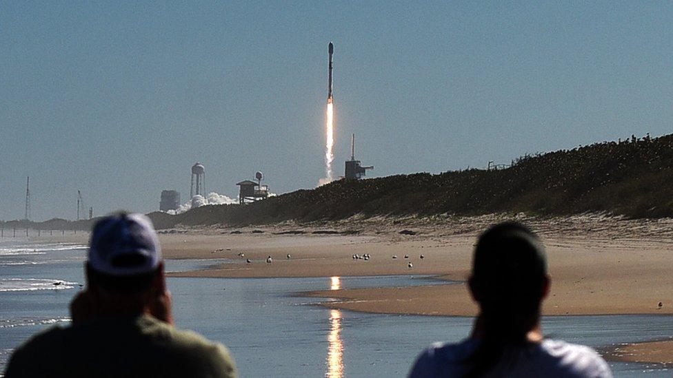 Onlookers watch a SpaceX Falcon 9 rocket launch from Cape Canaveral, carrying 49 Starlink satellites