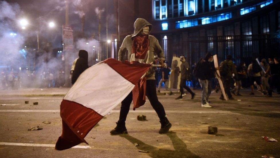 Protester carries a Peruvian flag during clashes in Lima on 14 November 2020