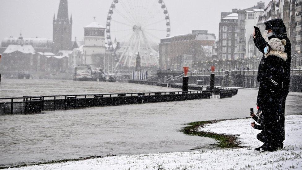 People walk along the Rhine promenade during the snowfall