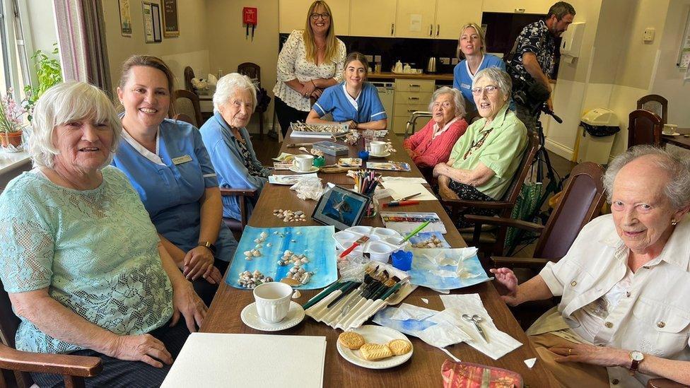 A group of elderly residents sitting around a table