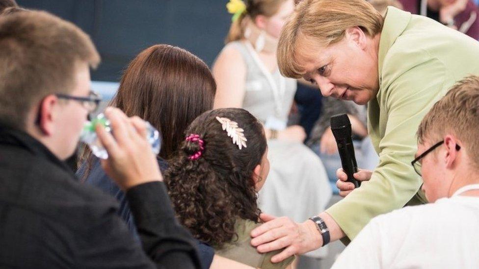 Handout photo made available by the German government press office on July 16 2015 shows German Chancellor Angela Merkel (R) comforting a a crying Palestinian girl threatened with deportation on July 15, 2015 in Rostock, northern Germany.