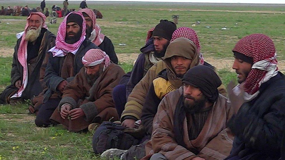 Militant men sit down with their heads covered