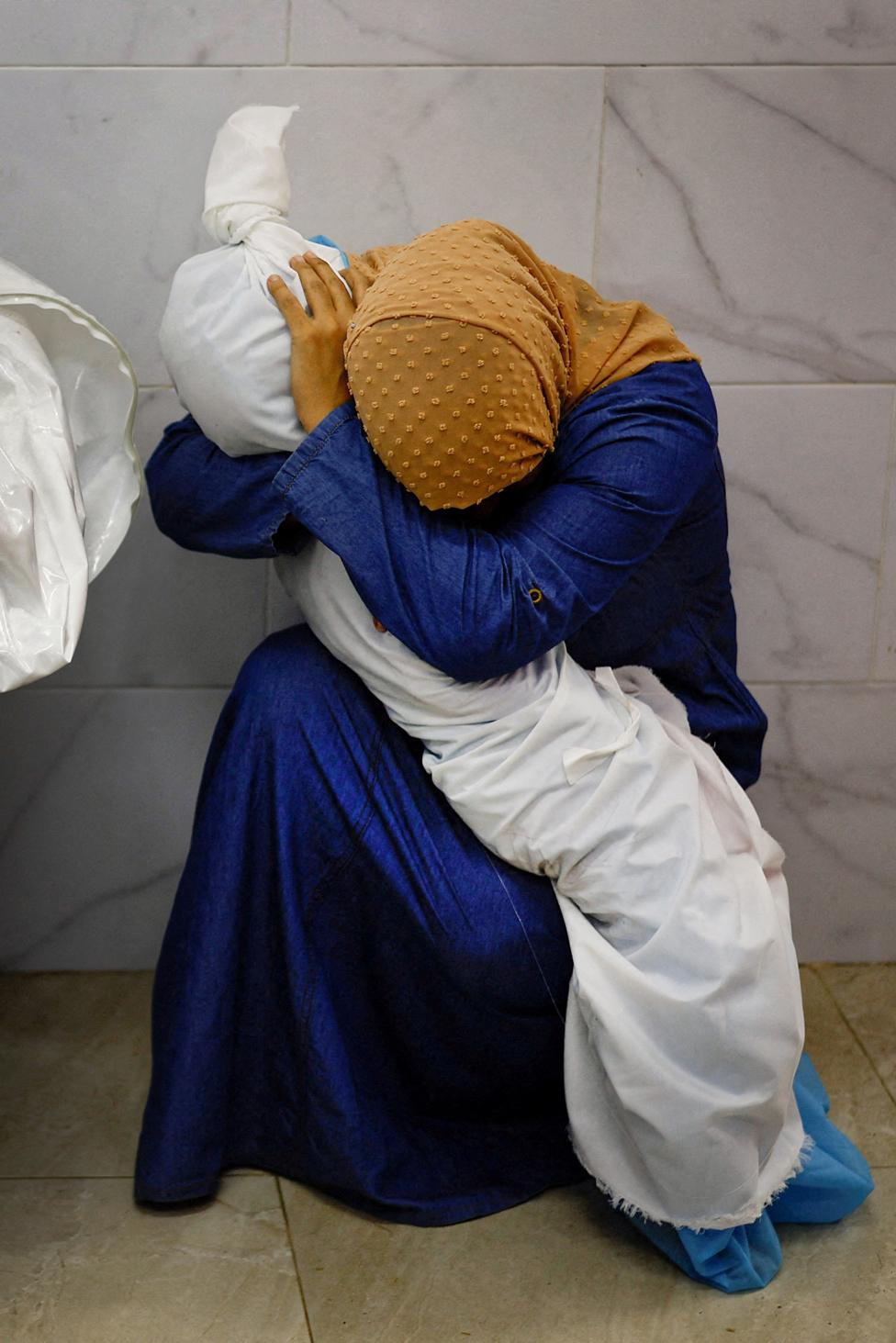 Palestinian woman Inas Abu Maamar, 36, embraces the body of her 5-year-old niece Saly, who was killed in an Israeli strike, at Nasser hospital in Khan Younis in the southern Gaza Strip, October 17, 2023.