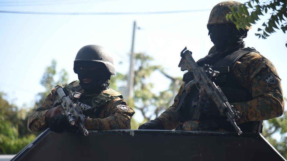 Police of the National Palace stand guard on a street in the commune of Petion Ville, in the Haitian capital Port-au-Prince