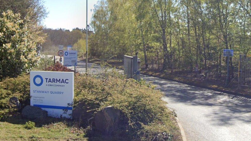 Entrance to quarry with long dust road and Tarmac sign