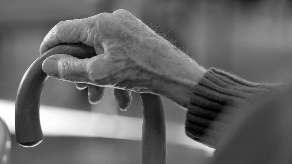 Older person holding walking stick