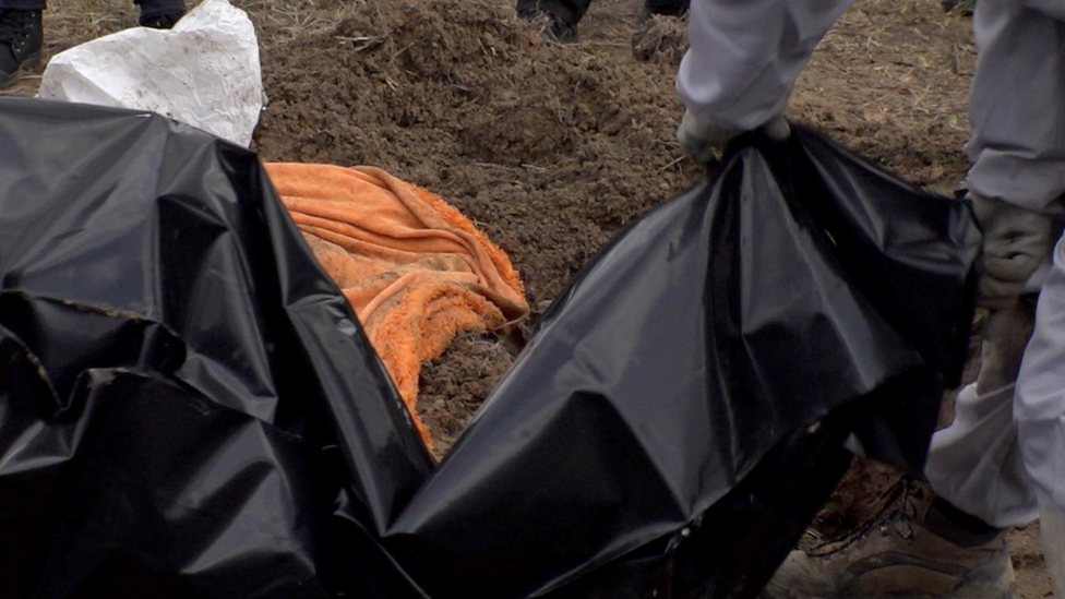 Investigators prepare body bags for victims at a mass grave in Bucha, near Kyiv