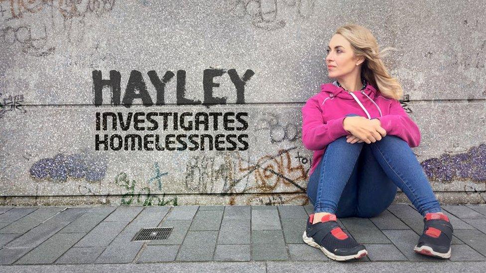 Reporter Hayley looks to her right, sitting on the ground next to a wall covered in graffiti. Next to her are the words 'Hayley investigates homelessness'