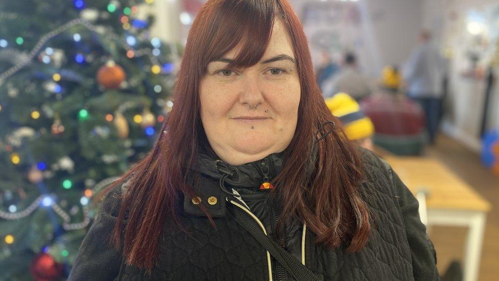 Woman at charity hub with Christmas decorations in the background