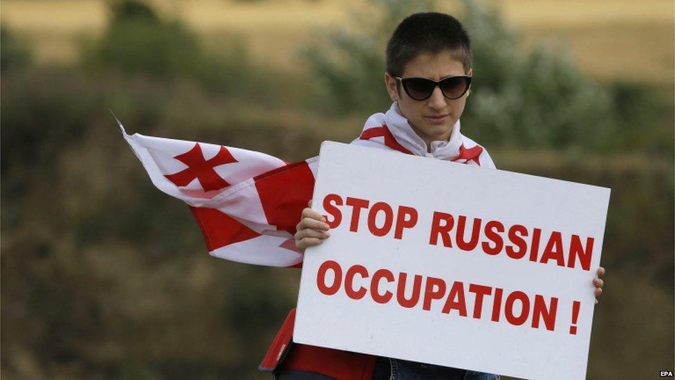 A Georgian protester holds a placard reading "Stop Russian Occupation" during an anti-Russian rally near the border between Georgia and the breakaway region of South Ossetia, 14 July 2015