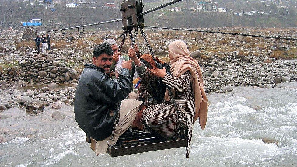 Pakistani's sit on a makeshift cable car to cross a river to get to their home in 2007