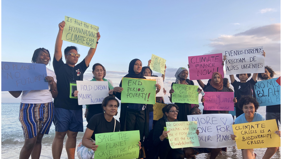 Young climate activists holding up signs