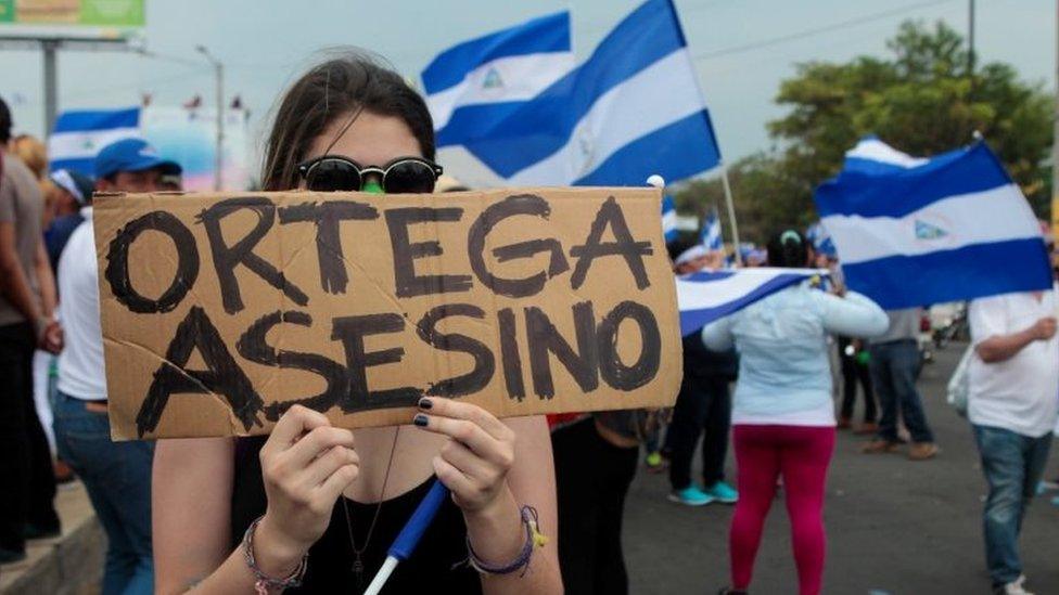 A demonstrator holds a sign that reads "Ortega Killer" during a protest march against Nicaraguan President Daniel Ortega's government in Managua, Nicaragua May 9, 2018.