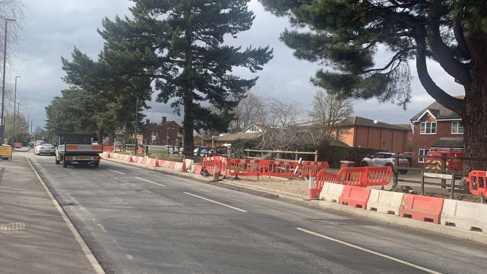 Straight road with extensive roadwork barrier on one side.