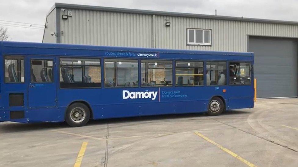 A blue bus in front of a warehouse