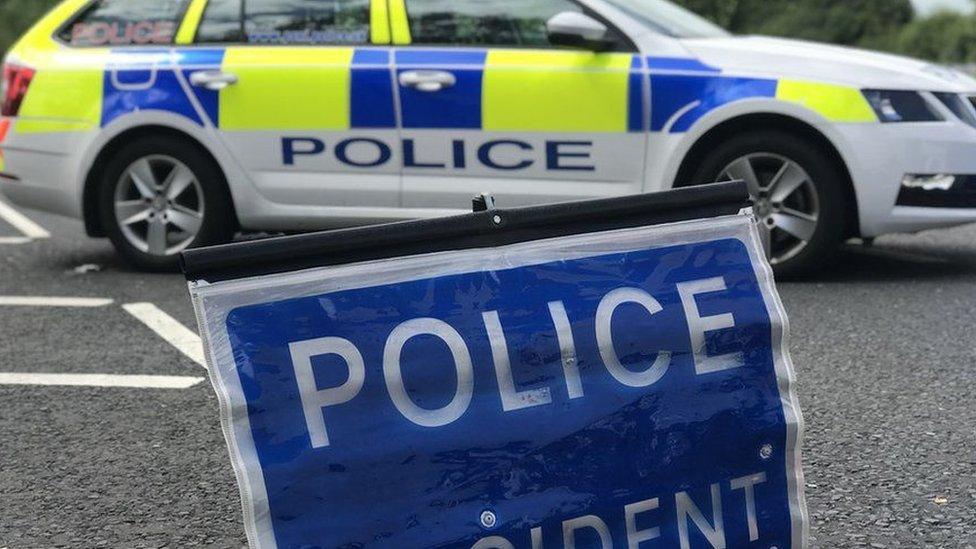 A police car parked next to a sign that reads: POLICE - ACCIDENT