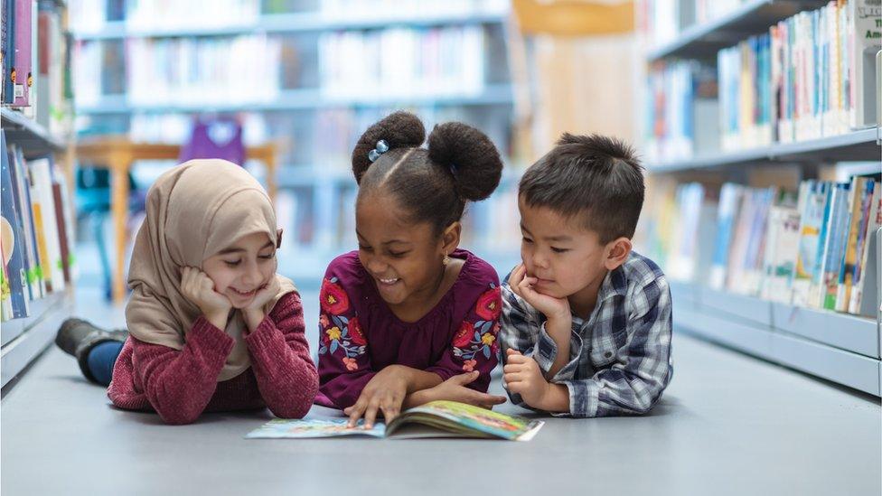 Kids on floor reading a book