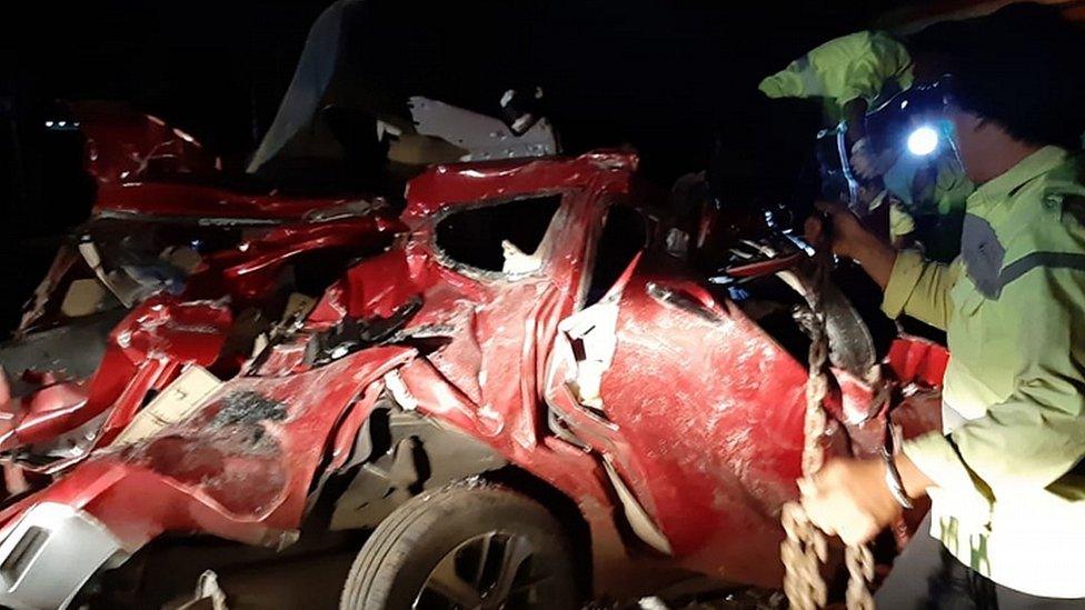 Picture released by West Java Police shows officers inspecting the wreckage of a car involved in an accident with a coach on a toll road in Majalengka, West Java