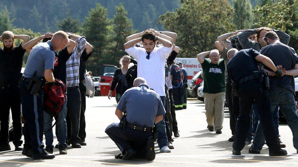 Police search students outside Umpqua Community College in Roseburg, Ore., Thursday, Oct. 1, 2015, following a deadly shooting at the college.