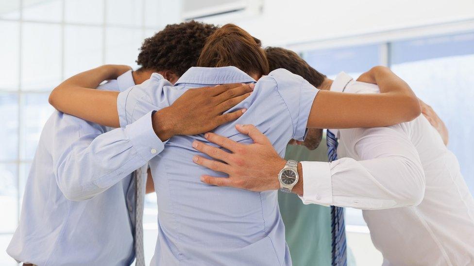 Business team with heads together forming a huddle