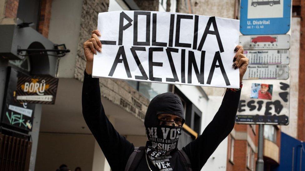 A demonstrator holds a banner that reads 'Killer Police' during a rally in Bogota, Colombia on August 26, 2021.