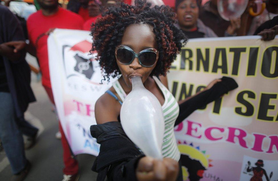 A Kenyan female sex worker plays with an inflated condom as she walks with supporters and members of the lesbian, gay, bisexual and transgender (LGBT) community