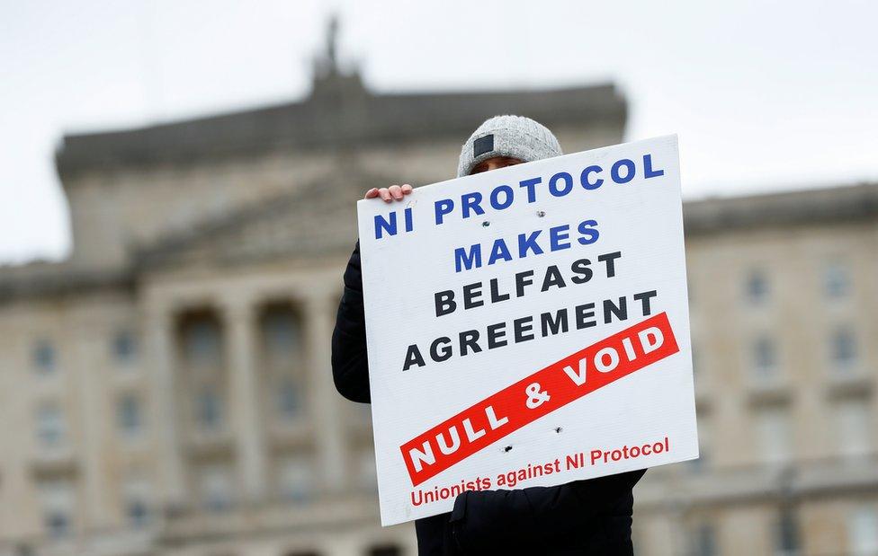 A loyalist protester at Stormont holds a sign that reads: NI Protocol makes Belfast Agreement null and void - unionists against NI Protocol