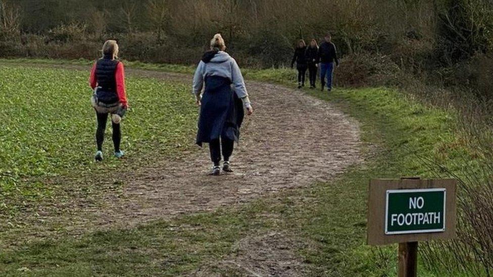 People walking off the footpath on crops