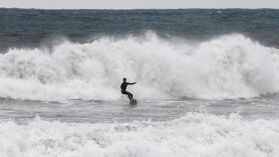 A surfer takes advantage of the big waves breaking at Barceloneta beach in Barcelona, Spain