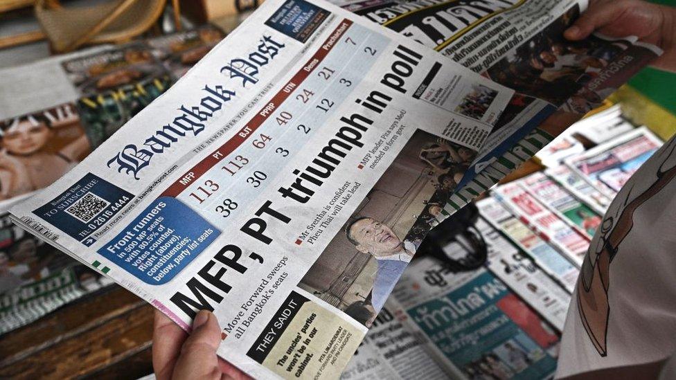 A man reads a Thai newspaper featuring front page coverage of Thailand's general election at a newsstand in Bangkok on May 15, 2023