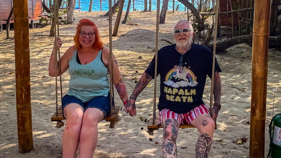 Kazzy and Lee on a swing on the beach holding hands