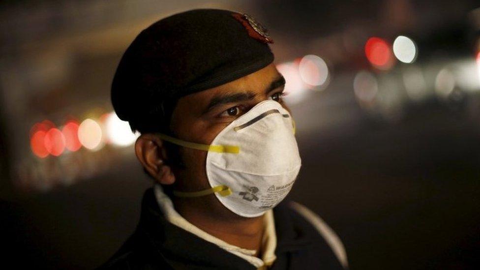 A traffic policeman wears a mask to protect himself from dust and air pollution as he stands on a road-divider in New Delhi, India, December 23, 2015