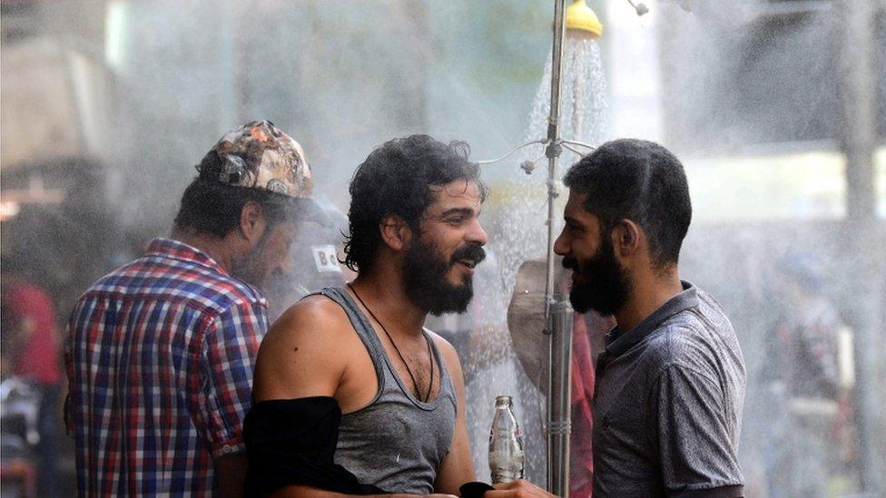 Two men stand under an outside shower in central Baghdad