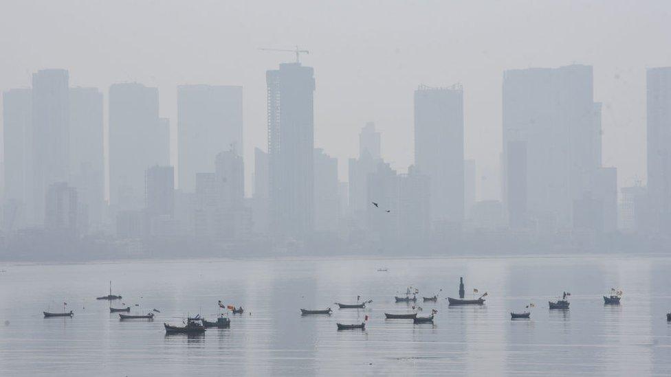 Bandra district in Mumbai hidden behind a haze with fishing boats in the front.