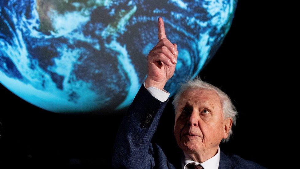 Sir-David-Attenborough-pointing-at-a-picture-of-Earth.