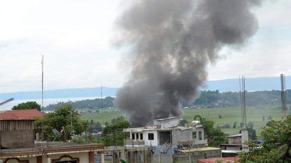 Black smoke billows from burning houses as fighting between Philippine soldiers and the IS-affiliated Maute group rages near the provincial capitol in Marawi, on the southern island of Mindanao on 25 May 2017