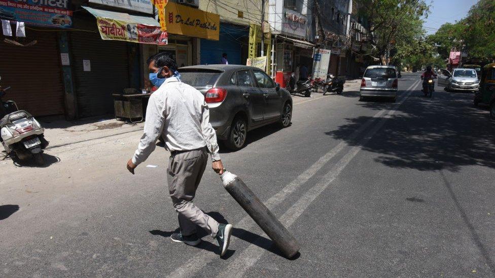 A family member of Covid-19 patient carries an empty cylinder to refill outside the oxygen filling centre at Dilshad Garden Area on April 25, 2021 in New Delhi, India.