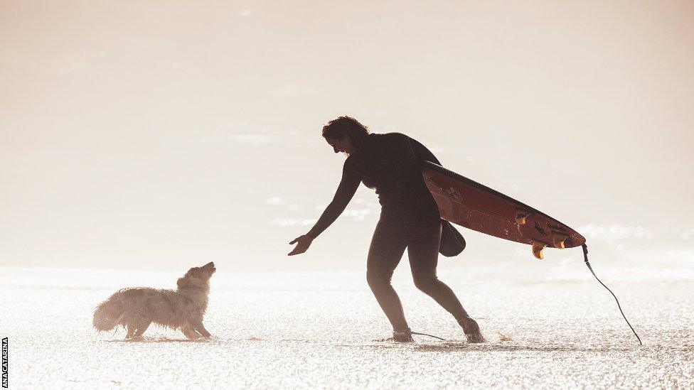 Maya plays with one of her dogs at Nazare