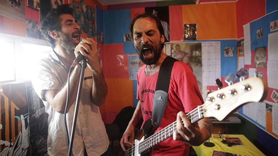 Two inmates sing and play the guitar in the music studio