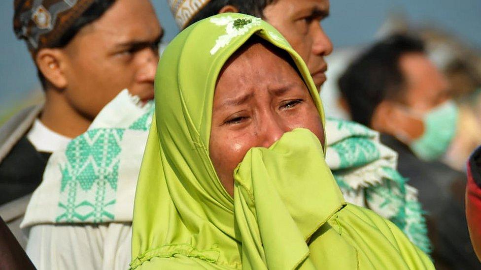 A woman cries as people look at the damages after an earthquake and a tsunami hit Palu