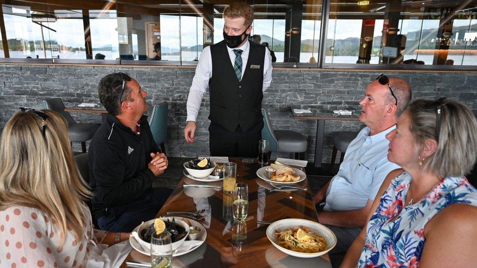 Diners at table, waiter wears mask