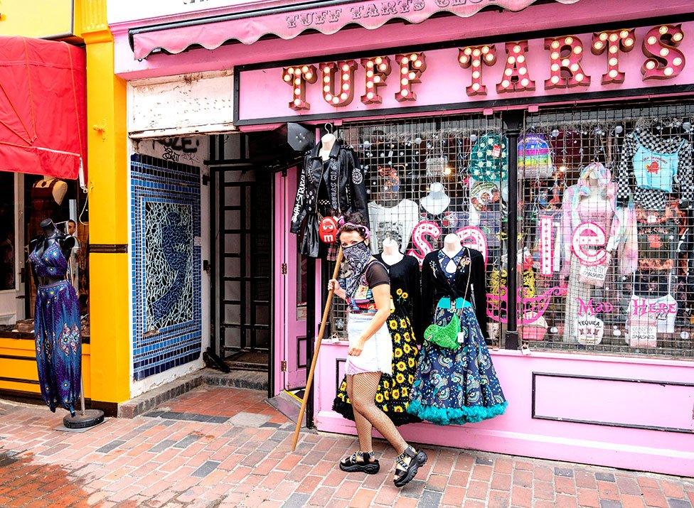 A worker prepares a fashion shop for customers