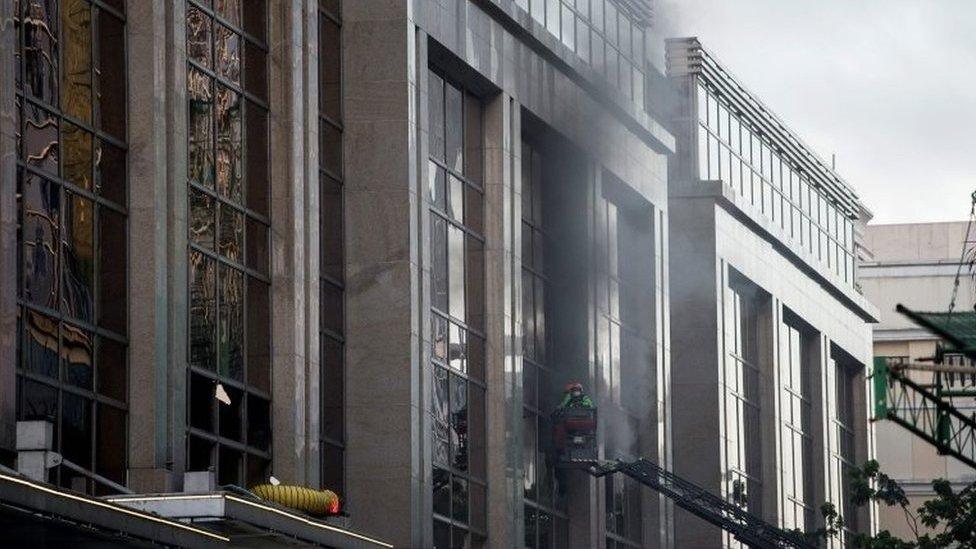 Firemen break a glass window of the Resorts World Hotel following an assault in Manila on 2 June 2017.