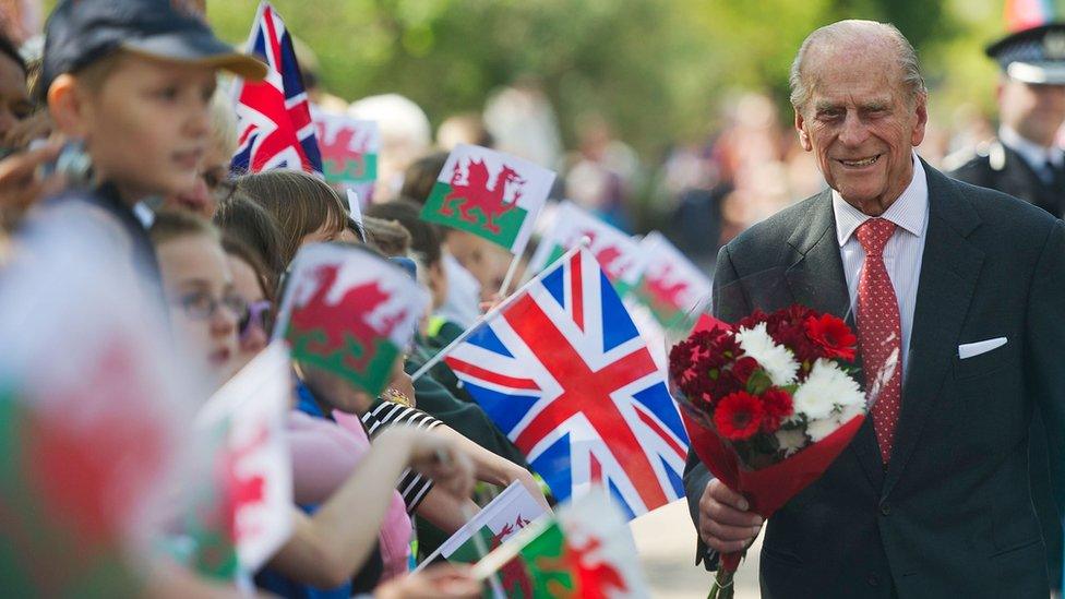 The Duke of Edinburgh receives flowers from local children at the Royal Dockyard Chapel during an official visit on April 29, 2014 in Pembroke Dock