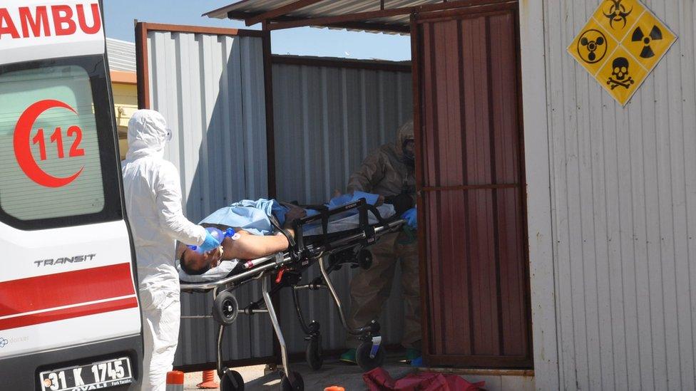 Turkish officials wearing hazard suits move an injured man on a stretcher near the Syrian border (4 April 2017)