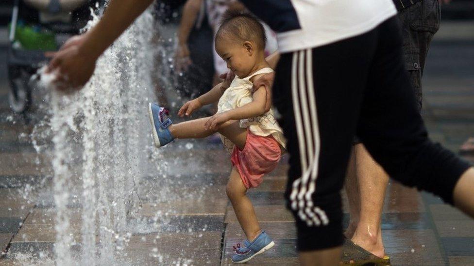 In this July 13, 2015 file photo, a child plays near water fountains at a shopping mall in Beijing