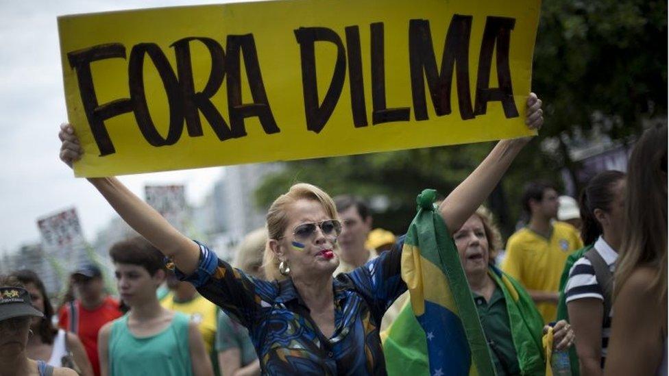 In this Dec. 13, 2015 file photo, a woman holds a sign that reads in Portuguese; "Dilma Out" during a demonstration in favour of the impeachment of Brazil's President Dilma Rousseff, on Copacabana beach in Rio de Janeiro, Brazil. J