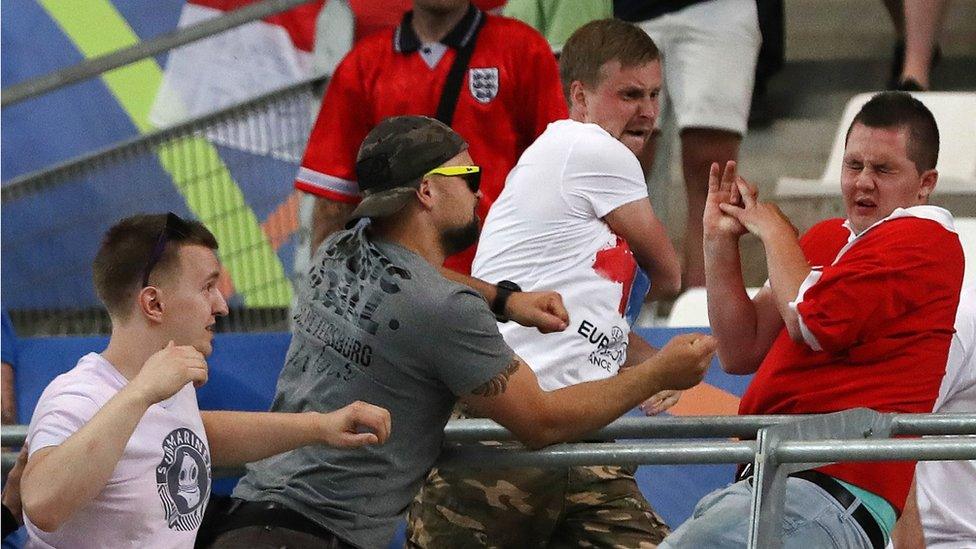 Man flinching in the stands while three others prepare to hit him, June 11 2016