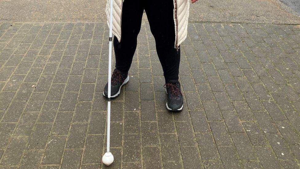 A person holding a white cane on a street